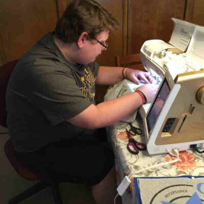 Evan participates in sewing his high school graduation T-Shirt Memory Quilt. 
